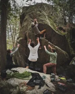 bouldering-tre-personer-som-hjälper-en-annan-upp-för-klippan
